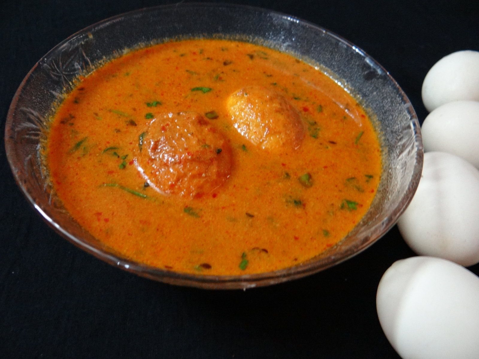 Halved boiled eggs in a rich tomato and coriander curry