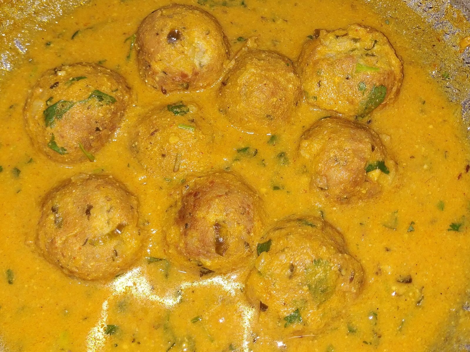 Kofta curry in a golden korma sauce, garnished with coriander