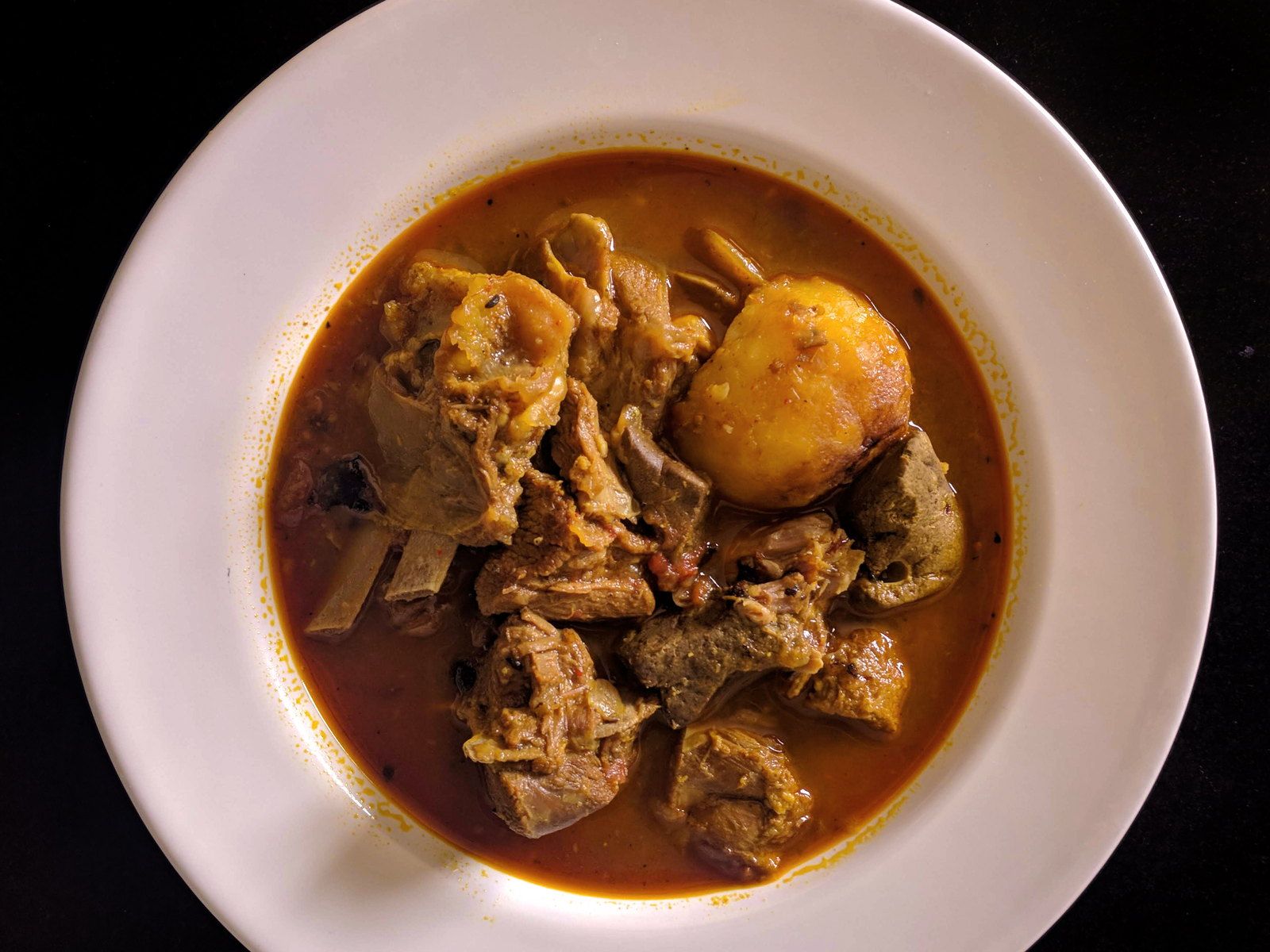 Goat curry with whole spices photographed on a dark background